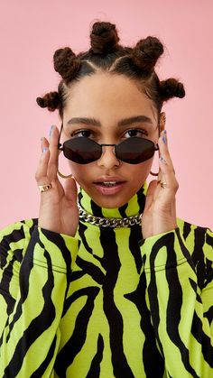 a woman wearing sunglasses and a yellow zebra print shirt is holding her hands up to her face