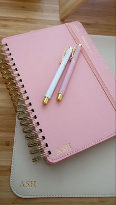 a pink notebook with a gold pen on top