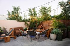 a woman sitting at a table on top of a patio surrounded by potted plants