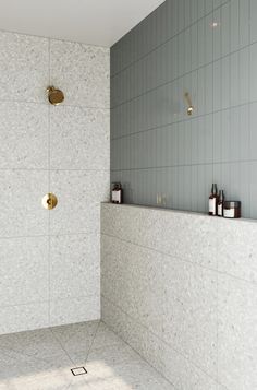 a white tiled bathroom with gold faucets and soap dispensers on the wall