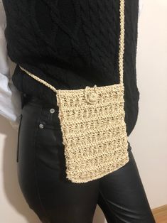 a woman wearing black pants holding a crocheted purse