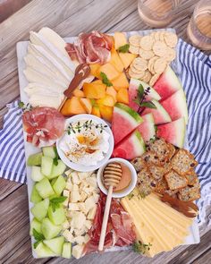 an assortment of cheeses, crackers and fruits on a platter