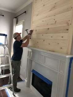 a man is painting the fireplace in his living room with white paint and wood paneling