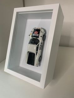 a toy car in a white shadow box