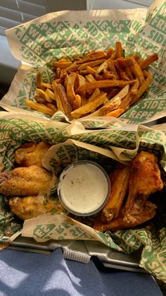 two baskets filled with chicken wings and french fries next to a cup of ranch dressing