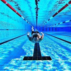 a man swimming in an indoor pool with poles sticking out of the water's surface