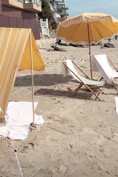 two beach chairs and an umbrella on the sand