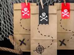 two brown paper bags with pirate symbols on them and some gold foil wrapped in twine