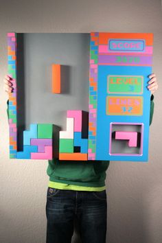 a person holding up a piece of art made out of legos and paper squares