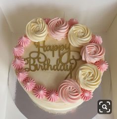 a birthday cake with white frosting and pink icing on it's side