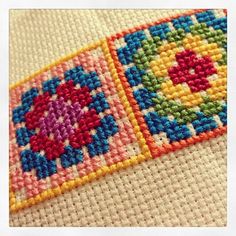 a close up view of a cross stitch pattern on a piece of cloth with the colors of the rainbow