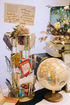 there is a globe and other items on display at the table with flowers in vases