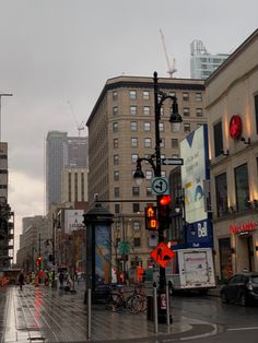 an empty city street with traffic lights and buildings in the background on a rainy day