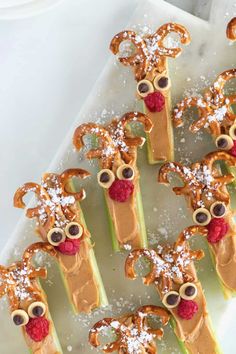 pretzels decorated with reindeer faces and raspberries are arranged on a white platter