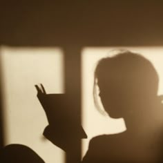 the shadow of a person holding a book in front of a window with light coming through it