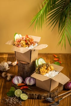 three boxes filled with food sitting on top of a wooden table next to some vegetables