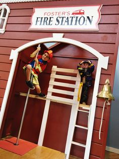 two figurines are sitting on top of a fire station sign and ladders