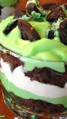 two desserts with green frosting and cookies on top sitting on a wooden table