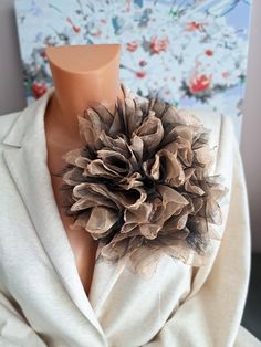 a mannequin wearing a white jacket with a brown flower on it