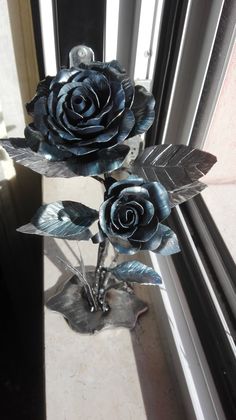 two metal roses sitting on top of a window sill