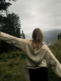 a woman with her arms spread out in the air on a path near some trees