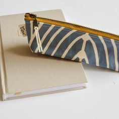 a blue and white striped zippered pouch sitting on top of a book