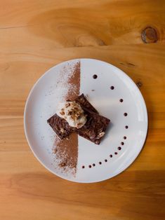 a piece of chocolate cake on a white plate with ice cream and sprinkles