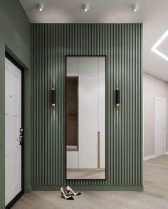 a pair of shoes sitting on the floor in front of a green wall and mirror