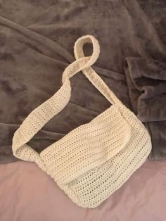 a white crocheted purse sitting on top of a bed next to a blanket