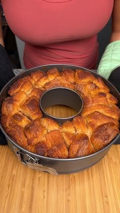 a bundt cake sitting on top of a wooden table next to a woman's stomach