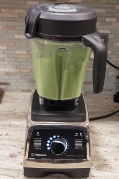 a blender filled with green liquid on top of a counter