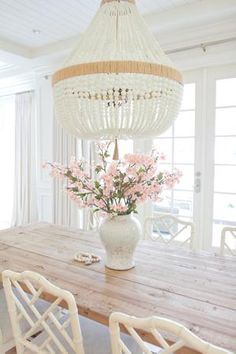 a dining room table with white chairs and a chandelier hanging from the ceiling