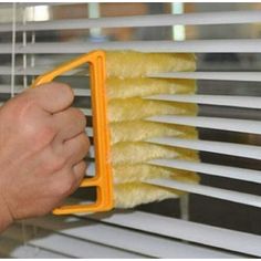 a person is cleaning the blinds with a brush