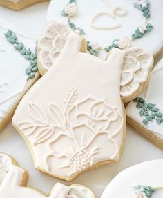 some decorated cookies are sitting on a white tablecloth with blue and green trimmings