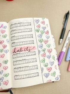 an open notebook with hearts on it next to markers, pens and pencils in the pages