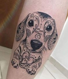 a black and white dog tattoo on the right leg, with an ornate design around it