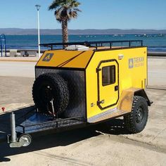 a yellow and black utility trailer parked on the side of the road next to the ocean