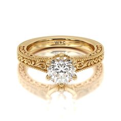 a yellow gold engagement ring with an oval diamond center and filigrees on the band