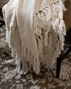 a white blanket sitting on top of a wooden table next to a rug and chair