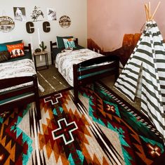 two beds in a room with colorful rugs on the floor and pillows on the wall