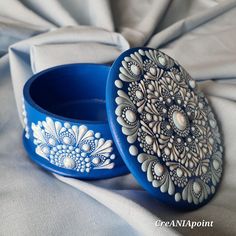 two blue and white decorated bangles sitting on top of a cloth covered tablecloth