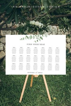 a seating chart for an outdoor wedding with greenery and white flowers on the table