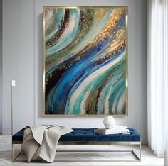 an abstract painting hangs on the wall above a blue bench