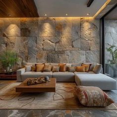 a modern living room with stone walls and floor to ceiling windows, large sectional couch