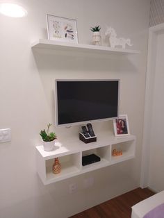 a flat screen tv sitting on top of a white shelf next to a wall mounted television