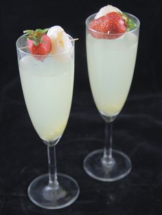 two glasses filled with white wine and topped with strawberries