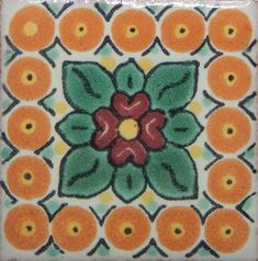 an orange and green tile with flowers on it