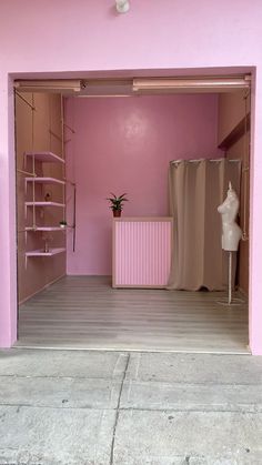 an empty room with pink walls and shelves on either side of the door, in front of a mannequin's head