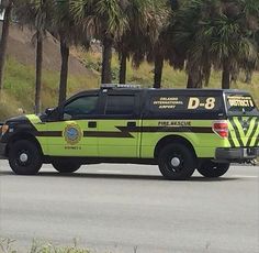 a yellow and black police truck driving down the street