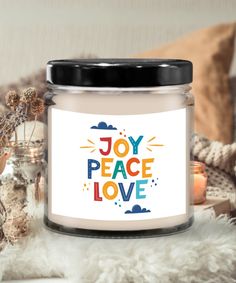 a candle with the words joy peace love on it next to some candles and other decorations